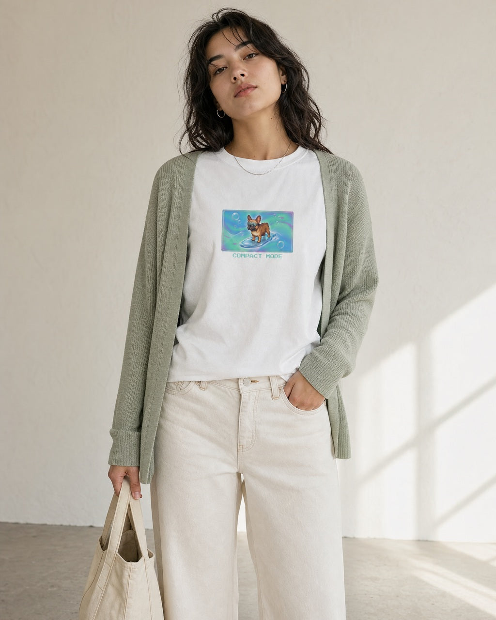 O's Tees Compact Mode French Bulldog Frutiger Aero Dogs graphic tee lifestyle image — White shirt, female shot 02, sage cardigan cream denim